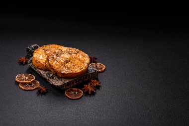 Balkabağı dilimlenmiş, biberiye ve baharatla kızartılmış, koyu beton bir arka planda.