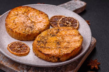 Balkabağı dilimlenmiş, biberiye ve baharatla kızartılmış, koyu beton bir arka planda.