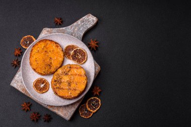 Balkabağı dilimlenmiş, biberiye ve baharatla kızartılmış, koyu beton bir arka planda.