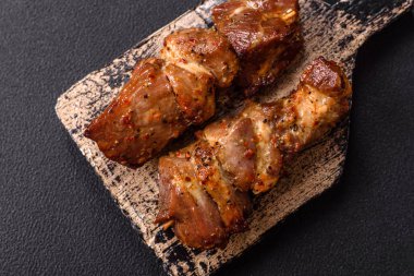 Lezzetli ızgara tavuk, hindi ya da domuz şişi, tuzlu, baharatlı ve otlu, koyu beton bir arka planda.