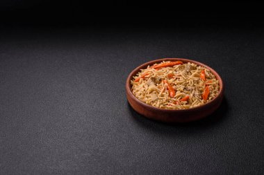 Lezzetli taze pilav, pirinç, havuç, et, soğan, baharat ve böğürtlen ile koyu beton arka planda seramik bir tabakta.