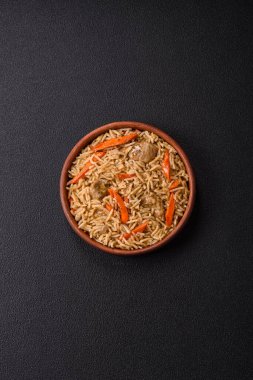 Lezzetli taze pilav, pirinç, havuç, et, soğan, baharat ve böğürtlen ile koyu beton arka planda seramik bir tabakta.