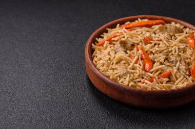 Lezzetli taze pilav, pirinç, havuç, et, soğan, baharat ve böğürtlen ile koyu beton arka planda seramik bir tabakta.