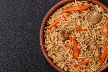 Lezzetli taze pilav, pirinç, havuç, et, soğan, baharat ve böğürtlen ile koyu beton arka planda seramik bir tabakta.