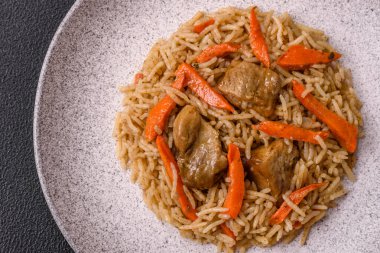 Lezzetli taze pilav, pirinç, havuç, et, soğan, baharat ve böğürtlen ile koyu beton arka planda seramik bir tabakta.