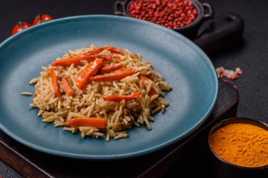 Lezzetli taze pilav, pirinç, havuç, et, soğan, baharat ve böğürtlen ile koyu beton arka planda seramik bir tabakta.