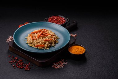 Lezzetli taze pilav, pirinç, havuç, et, soğan, baharat ve böğürtlen ile koyu beton arka planda seramik bir tabakta.