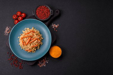 Lezzetli taze pilav, pirinç, havuç, et, soğan, baharat ve böğürtlen ile koyu beton arka planda seramik bir tabakta.