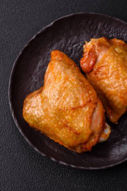 Koyu beton arka planda tuz, baharat ve otlarla kızartılmış tavuk butları.