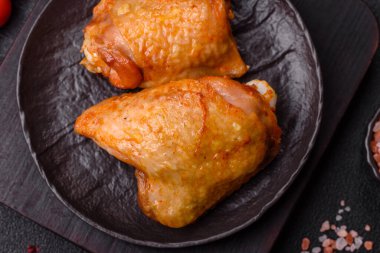 Koyu beton arka planda tuz, baharat ve otlarla kızartılmış tavuk butları.