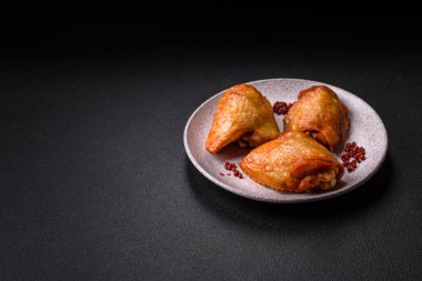 Koyu beton arka planda tuz, baharat ve otlarla kızartılmış tavuk butları.