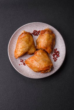 Koyu beton arka planda tuz, baharat ve otlarla kızartılmış tavuk butları.