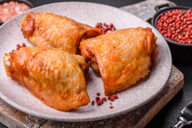 Koyu beton arka planda tuz, baharat ve otlarla kızartılmış tavuk butları.