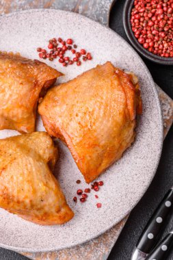 Koyu beton arka planda tuz, baharat ve otlarla kızartılmış tavuk butları.