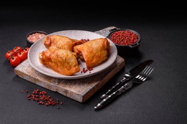 Koyu beton arka planda tuz, baharat ve otlarla kızartılmış tavuk butları.