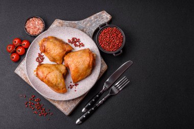 Koyu beton arka planda tuz, baharat ve otlarla kızartılmış tavuk butları.