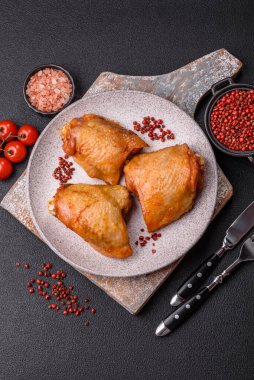 Koyu beton arka planda tuz, baharat ve otlarla kızartılmış tavuk butları.