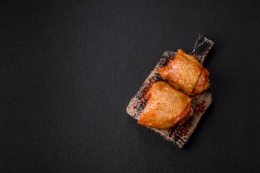 Koyu beton arka planda tuz, baharat ve otlarla kızartılmış tavuk butları.