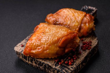 Koyu beton arka planda tuz, baharat ve otlarla kızartılmış tavuk butları.