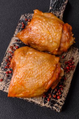 Koyu beton arka planda tuz, baharat ve otlarla kızartılmış tavuk butları.