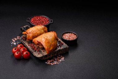 Koyu beton arka planda tuz, baharat ve otlarla kızartılmış tavuk butları.