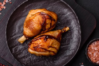 Lezzetli ızgara tavuk bacağı. Baharatlı ve otlu teriyaki soslu. Koyu beton arka planda.