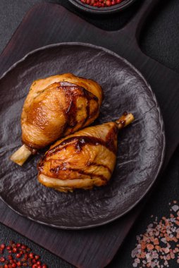 Lezzetli ızgara tavuk bacağı. Baharatlı ve otlu teriyaki soslu. Koyu beton arka planda.