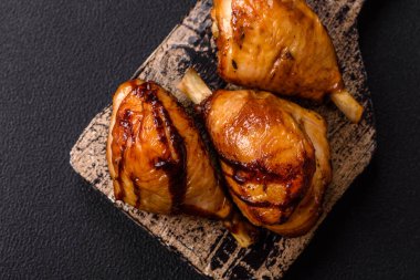 Lezzetli ızgara tavuk bacağı. Baharatlı ve otlu teriyaki soslu. Koyu beton arka planda.