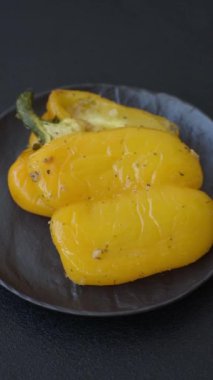 İkiye bölünmüş sarı tatlı biber ve koyu beton arka planda tuz, baharat ve otlarla ızgara.