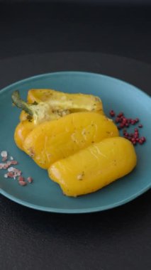 İkiye bölünmüş sarı tatlı biber ve koyu beton arka planda tuz, baharat ve otlarla ızgara.