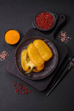 İkiye bölünmüş sarı tatlı biber ve koyu beton arka planda tuz, baharat ve otlarla ızgara.