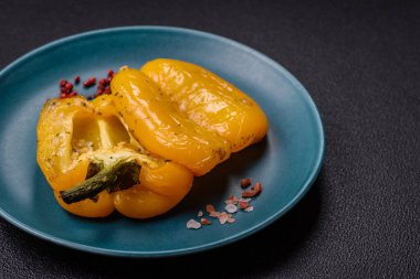 İkiye bölünmüş sarı tatlı biber ve koyu beton arka planda tuz, baharat ve otlarla ızgara.