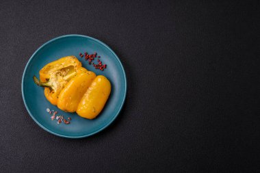 İkiye bölünmüş sarı tatlı biber ve koyu beton arka planda tuz, baharat ve otlarla ızgara.