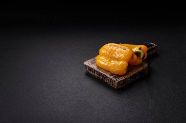 İkiye bölünmüş sarı tatlı biber ve koyu beton arka planda tuz, baharat ve otlarla ızgara.