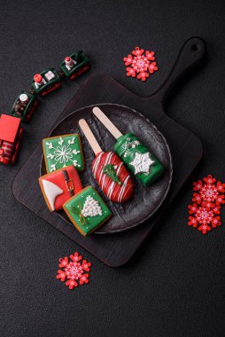 Çubuğun üzerinde noel ve yeni yılın stili ve renginde koyu beton bir zeminde çikolatayla kaplı doğal buzlu dondurma.