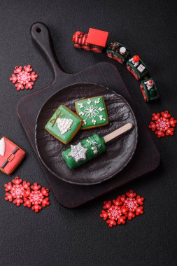 Çubuğun üzerinde noel ve yeni yılın stili ve renginde koyu beton bir zeminde çikolatayla kaplı doğal buzlu dondurma.