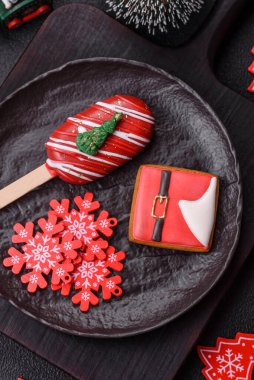 Çubuğun üzerinde noel ve yeni yılın stili ve renginde koyu beton bir zeminde çikolatayla kaplı doğal buzlu dondurma.