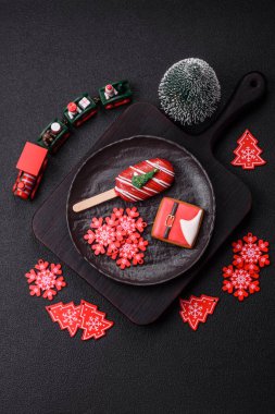 Çubuğun üzerinde noel ve yeni yılın stili ve renginde koyu beton bir zeminde çikolatayla kaplı doğal buzlu dondurma.