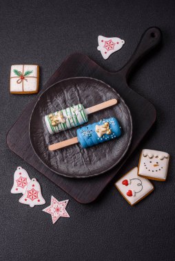 Çubuğun üzerinde noel ve yeni yılın stili ve renginde koyu beton bir zeminde çikolatayla kaplı doğal buzlu dondurma.