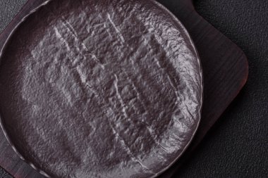 Koyu beton arka planda boş siyah seramik plaka. Aile yemeği için masayı hazırlıyorum.