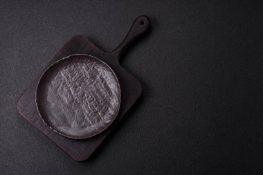 Koyu beton arka planda boş siyah seramik plaka. Aile yemeği için masayı hazırlıyorum.