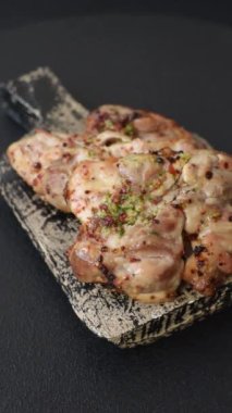 Koyu beton bir arka planda tuzlu, baharatlı ve otlu ızgara kemiksiz tavuk budu.