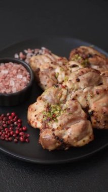 Koyu beton bir arka planda tuzlu, baharatlı ve otlu ızgara kemiksiz tavuk budu.