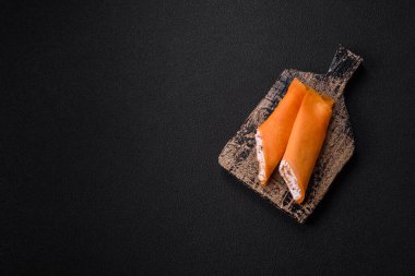 Krep krem peynirle yuvarlandı. Tatlı veya ekşi, koyu beton arka planda.