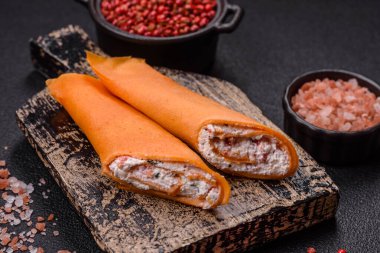 Krep krem peynirle yuvarlandı. Tatlı veya ekşi, koyu beton arka planda.