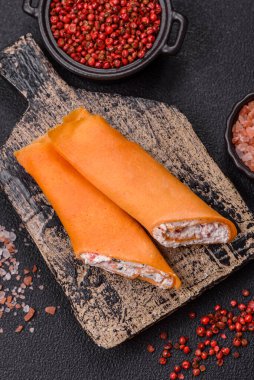 Krep krem peynirle yuvarlandı. Tatlı veya ekşi, koyu beton arka planda.