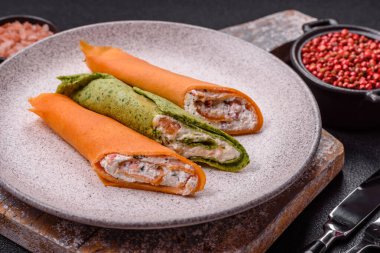 Krep krem peynirle yuvarlandı. Tatlı veya ekşi, koyu beton arka planda.