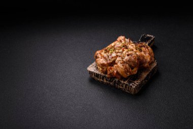 Koyu beton bir arka planda tuzlu, baharatlı ve otlu ızgara kemiksiz tavuk budu.