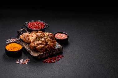 Koyu beton bir arka planda tuzlu, baharatlı ve otlu ızgara kemiksiz tavuk budu.