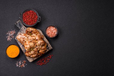 Koyu beton bir arka planda tuzlu, baharatlı ve otlu ızgara kemiksiz tavuk budu.